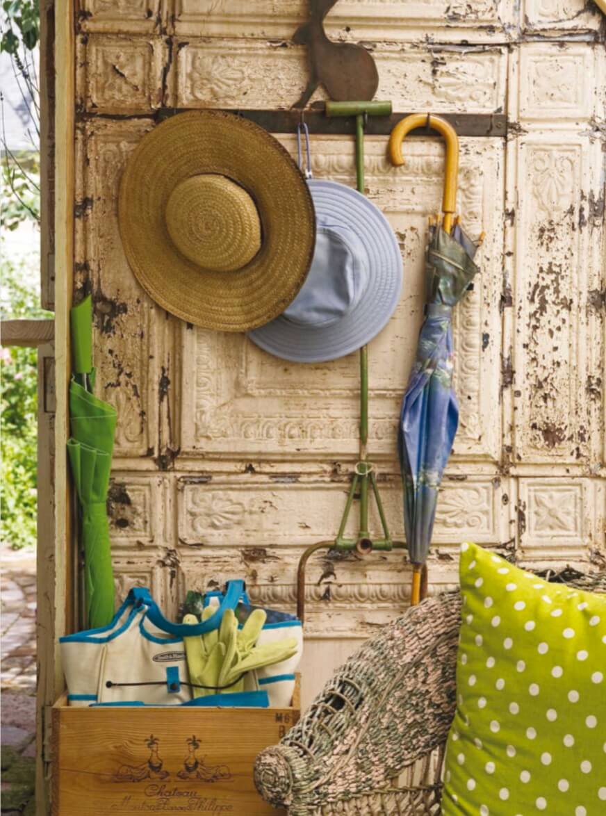 Just inside the greenhouse door, a French wine crate stores garden tools and a bunny hook rack keeps sun hats and umbrellas within easy reach. 