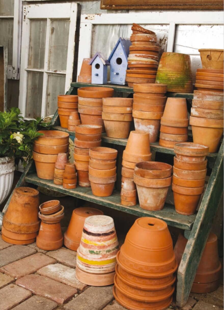 Opposite: A set of old steps in the greenhouse are stacked with dozens of terra-cotta pots that are more than a handsome tableau: The clay pots, along with the floor bricks, absorb daytime warmth and release it on cold nights.