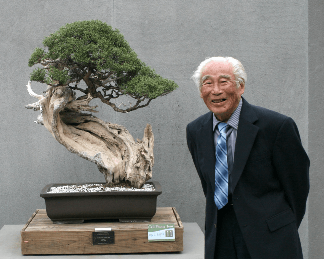 Năm 2009, Harry Hirao chụp ảnh bên cạnh món quà ông quyên tặng cho National Bonsai & Penjing Museum (Bảo tàng Cây cảnh & Hòn non bộ Quốc gia) vào năm 2004, một cây Bách Xù California (Juniperus californica, California juniper) mà ông đã sưu tập vào năm 1960. Ảnh: U.S. National Arboretum (Vườn ươm Quốc gia Hoa Kỳ.)