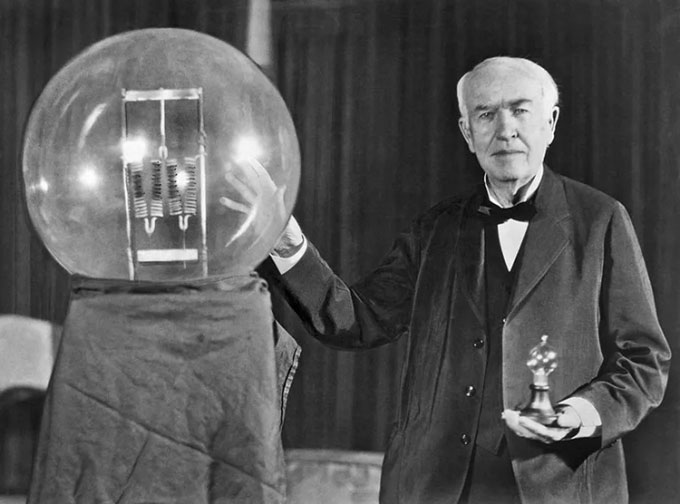 Thomas Edison cầm trên tay bóng đèn sợi đốt tại một bữa tiệc ở New Jersey, Mỹ
