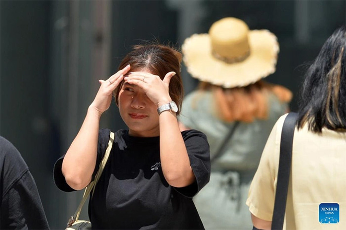 Một người đi bộ lấy tay che nắng khi đi ở Bangkok, Thái Lan